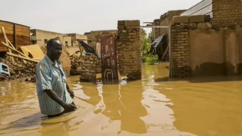 Getty Images Man wading through floodwater