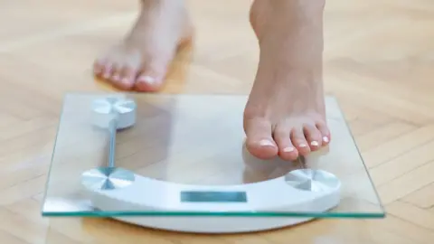 Getty Images woman stepping onto the scales