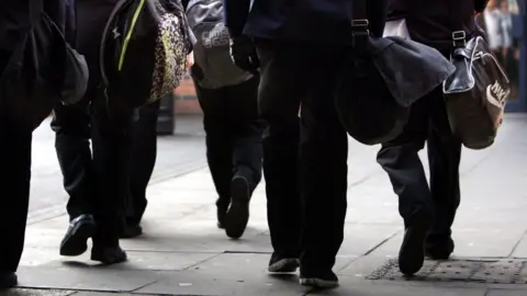 PA Media File image of anonymous pupils walking with school bags