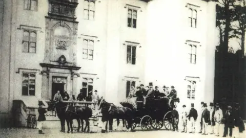 Antrim and Newtownabbey Borough Council Black and white photograph of a horse-drawn coach party outside Antrim castle