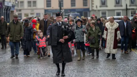 Phil Wilkinson A piper leads a procession through Kelso to mark the opening day.