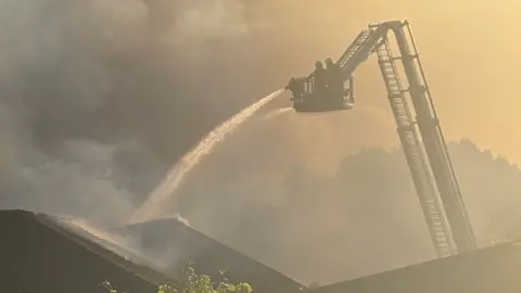 Daniel Storr Firefighters using an aerial platform to tackle the blaze with a lot of smoke obscuring the picture.