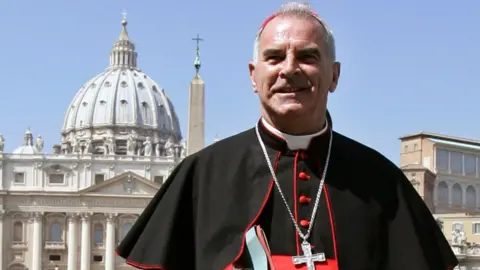 Reuters Cardinal Keith O'Brien wearing cassock and with silver crucifix standing in St Peter's Square in Rome with St Peter's dome in the background