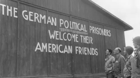 US Army/Getty Images Soldiers of the 46th Armored Infantry, 5th Armored Division, US Ninth Army, and their guide read, 'THE GERMAN POLITICAL PRISONERS WELCOME THEIR AMERICAN FRIENDS,' painted on the outside wall of one of the barracks of the political prisoners at the Buchenwald concentration camp, near Weimar, Germany