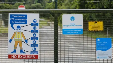 Getty Images A general view picture of the gate into Henley sewage treatwork works, which has signs on it, including a post on the left which says: 'The minimum PPE requirements for the site are' with a diagram of a man with PPE on. It says "NO EXCUSES in white littering on a read background underneath it.