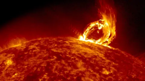 NASA/SDO The image shows the fiery orange surface of the Sun with an ejection of what looks like an arch of flames protruding from the surface on the right. This is a coronal mass ejection - a sudden blast of solar plasma and magnetic fields that the Sun sends into space