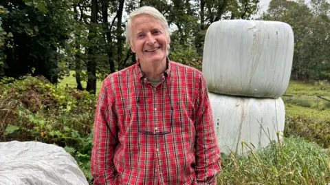 El granjero de carne Dave Braden con una camisa roja estampada y mirando a la cámara