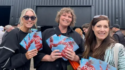 Nicolette Bosworth, Zoe Sussmeyer, and Georgina Hadjigeorgiou, from Pass It On, leafleting at the Notts County fan zone 'The Nest'.