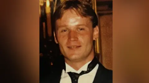 Steven Shevels with short brown hair. He is smiling and wearing a smart black jacket, black tie and white shirt.