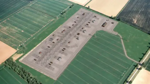 National Grid Artist impression of the proposed substation - a rectangle of concrete in a field with pylons and other structures