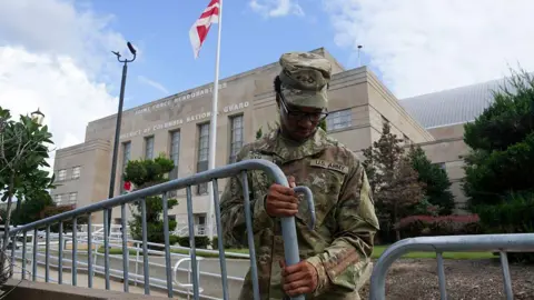 National Guard troops appear in Washington DC as mayor rejects 'authoritarian push' Getty Images A soldier erecting a barricade outside a government building