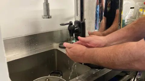 English pictured washing his hands using the tea urn. 