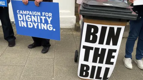 BBC A campaign posted for assisted dying, as well as one opposing it stuck to a brown bin