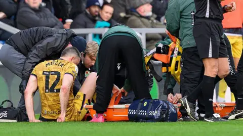 Lewis Miller is attended by medics on the pitch at Loftus Road
