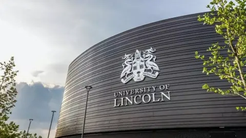 The black clad exterior of the University of Lincoln building with the university's coat-of-arms in white