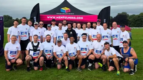 Menfulness A mixed group of men, dressed in white sports tops and dark shorts 