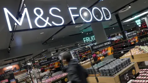 A customer walks through the food section of a Marks & Spencer (M&S) store