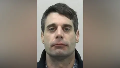 Northumbria Police Mugshot of Lockyer. He has faint stubble and short, thick black hair.