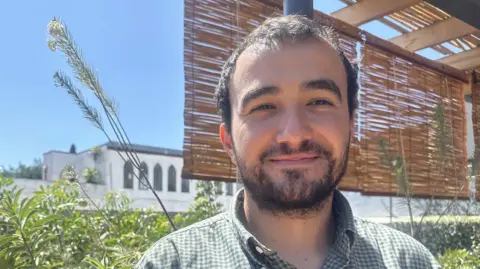 'Severo' cafe, Anwar Montoya standing outside with plants in the background