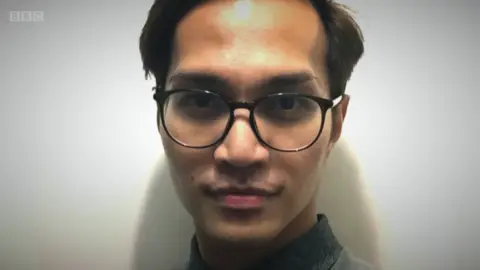 Reynhard Sinaga wears black-rimmed glasses and smiles at the camera