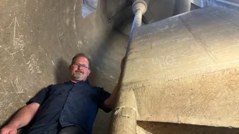 Chris Jarvis stands mid way up a windy stone staircase that leads to the tower.