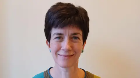 Rachel Ridley Rachel Ridley. She has short brown hair and is wearing green earrings.