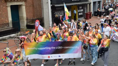 Pride Pictures & Kerry Kleis photography Last year's Reading Pride festival goers marching the streets of Reading holding LGBT flags and sign which reads "Proudly supporting the LGBT+ community".
