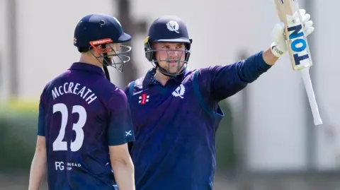 Mark Watt raises his bat having reached 50