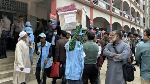 Aakriti Thapar/BBC A man carries a ballot box above his head amid a crowd of people in Bangladesh
