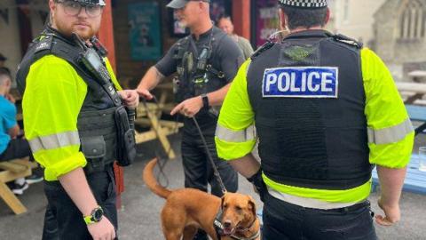 Three police officers and police dog Skye standing in a pub garden