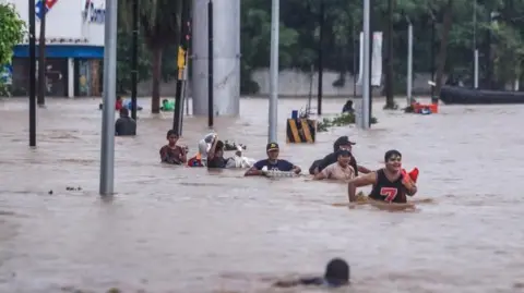 EPA People cross an avenue flooded by the passage of Hurricane John in the upper part of the port of Acapulco, in Guerrero, Mexico, 27 September 2024