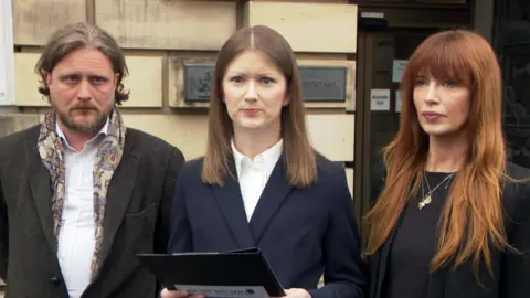 Three people wearing suits outside the High Court in Edinburgh