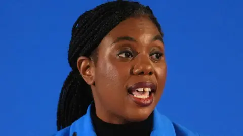 Kemi Badenoch against a blue backdrop