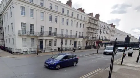 A four-storey cream building is on the left at the junction of the Parade and Clarendon Avenue in Leamington Spa. The Parade starts on the left of the photo and the road continues to the right.