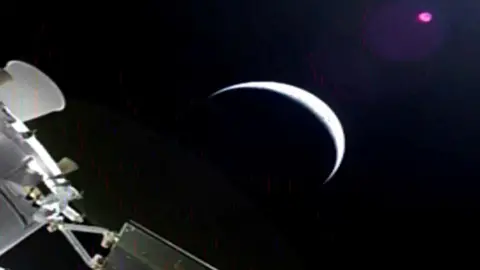 A sliver of the moon and parts of the orion spacecraft off to the side.