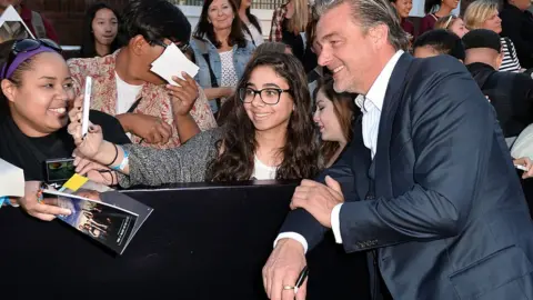 Getty Images Ray Stevenson poses for a photo with a fan on the red carpet in Los Angeles