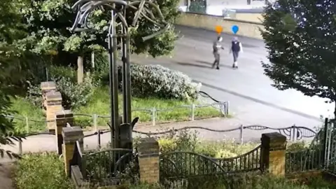 South Yorkshire Police A CCTV image capturing two people talking in the street. The entrance to a park is nearby.