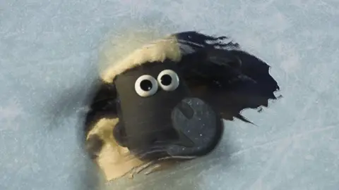 BBC / Ardman Animations Image of clay figure Shaun the Sheep, looking through a window covered in a white frost. 