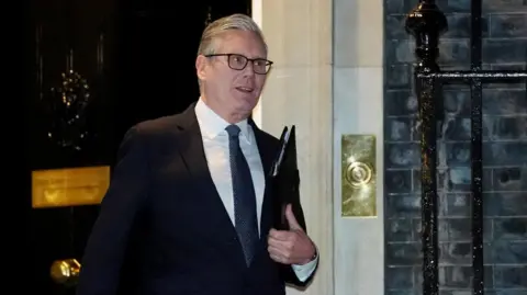 Starmer walking out of No 10 holding a black folder 