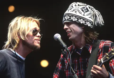 Getty Images Taylor Hawkins and Dave Grohl of the Foo Fighters perform as part of the Bridge School Benefit 2000 at Shoreline Amphitheatre on October 29, 2000 in Mountain View California.