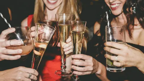 Getty Images A group of women holding drinks. They are laughing.