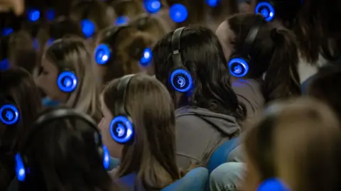 Mick Phipps Children sitting in an auditorium with headphones, taking part in the breathwork technique.