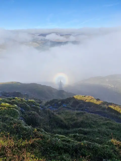 Christine Leishman Green hills with a cloudy sky and a halo in the centre of the photo