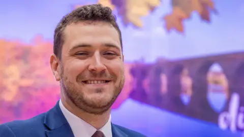 Andy Commins A close-up photo of Joe Morris, smiling; a man with short, brown hair.