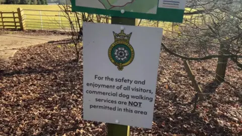 BBC/Nathan Turvey A sign, with the Yorkshire Agricultural Society logo, that reads: "For the safety and enjoyment of all visitors, commercial dog walking services are NOT permitted in this area".