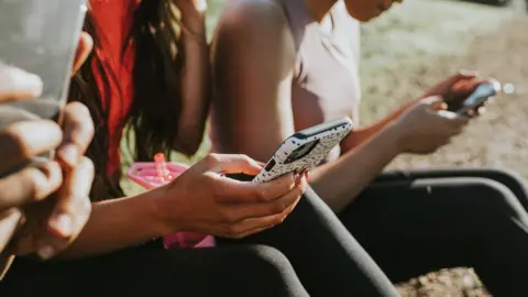 Getty Images women holding their phones