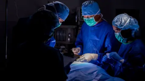 Getty Images Generic surgical team in blue scrubs performing operation on patient in hospital