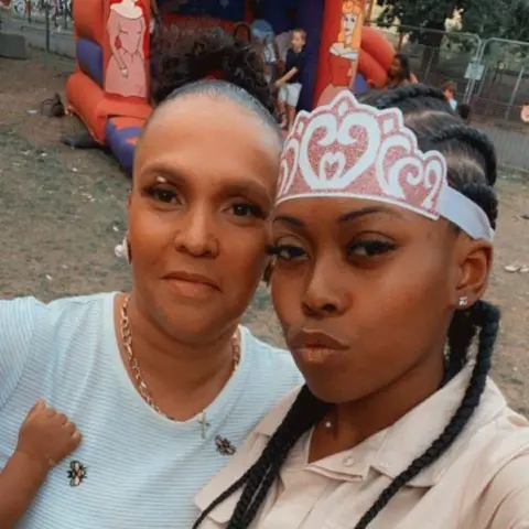 Family handout Fiona Holm with her arm around Savannah Holm-Aderemi, posing for a selfie. They are standing infront of a bouncy castle and Savannah is wearing a paper crown 
