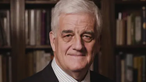 Reform UK Man with short white hair looking at the camera, he is wearing a striped shirt and black jacket.