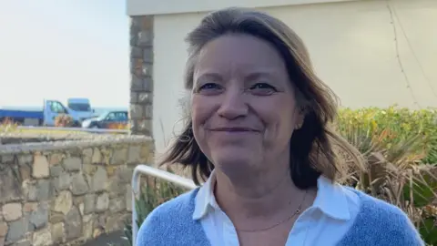 BBC Jo Le Noury. She has shoulder length brown hair and is wearing a bluie jumper. 